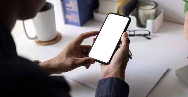 Vista de cerca del hombre que sostiene la pantalla en blanco del teléfono inteligente para su mensaje de texto o contenido de información