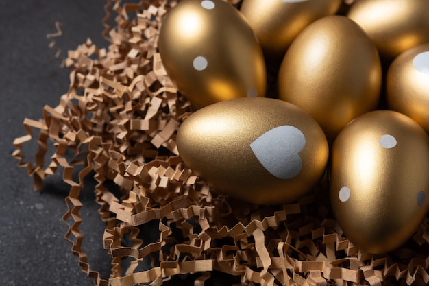 Vista de cerca de huevos de oro en un nido de papel sobre un fondo negro