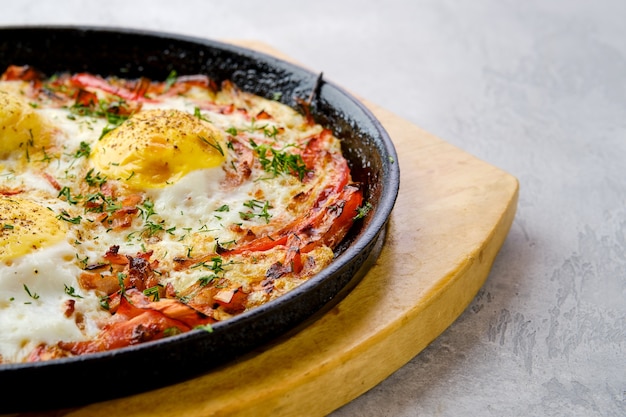 Vista de cerca de huevos con pimiento y tomate al horno en una sartén de hierro fundido