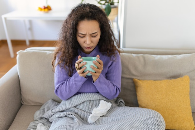 Vista de cerca de una joven asiática con una taza de bebida caliente en casa cubierta con una manta Gente bebe y concepto de ocio mujer joven con una taza de té o café en casa