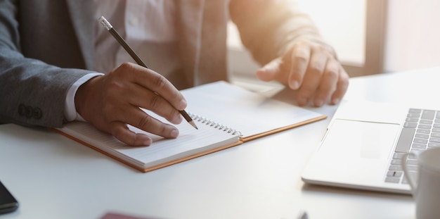 Vista de cerca del joven empresario profesional escribiendo sus conceptos de idea en el cuaderno