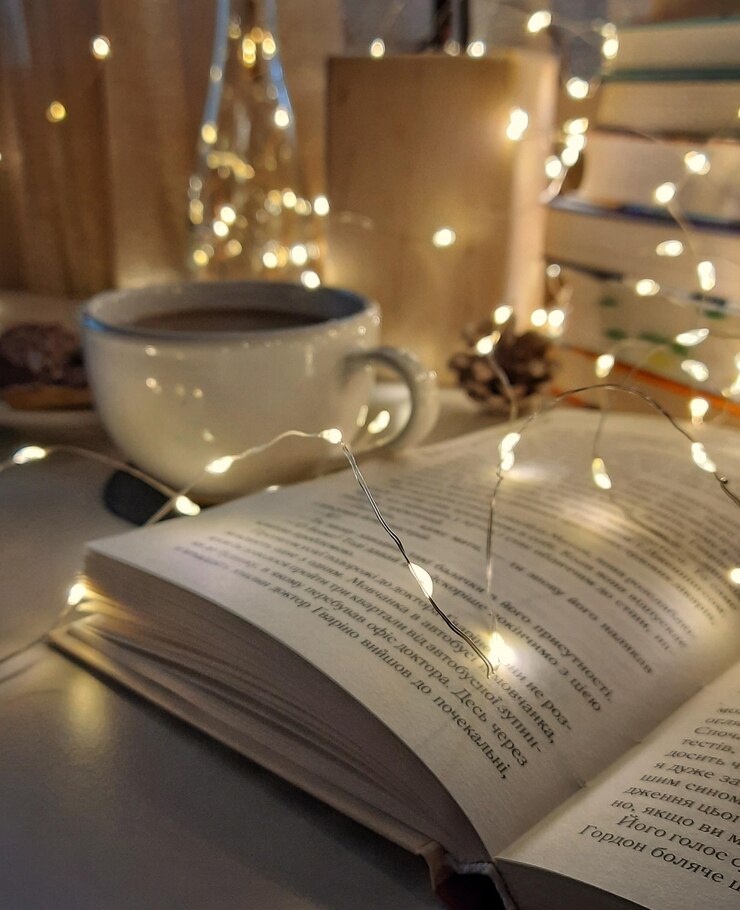 Vista de cerca de libros abiertos en la guirnalda trasera y taza de café