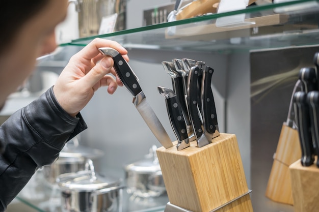 Vista de cerca de la mano del cliente eligiendo juego de cuchillos para cocina