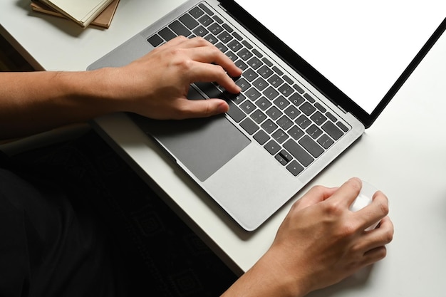 Foto vista de cerca de la mano escribiendo en el teclado de la computadora portátil en el escritorio de trabajo