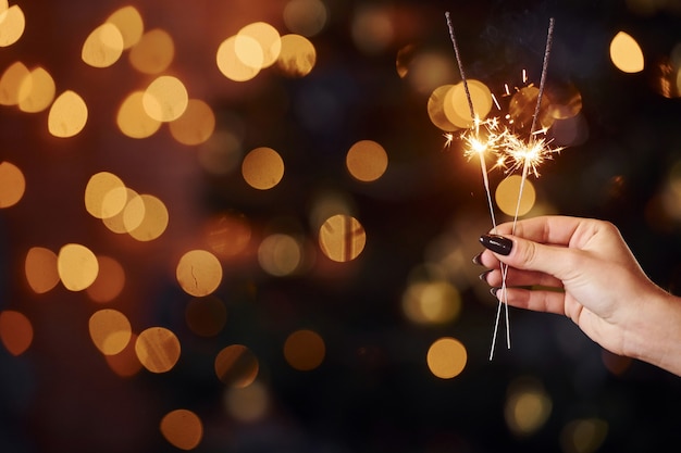 Vista de cerca de la mano de la mujer con bengala en el interior en las vacaciones de Navidad.