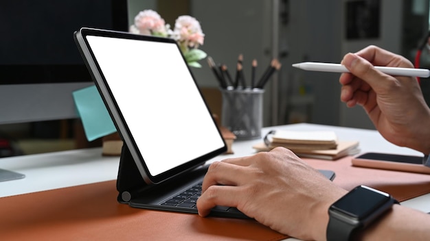 Vista de cerca de las manos de un hombre de negocios con un reloj inteligente sosteniendo un lápiz óptico y trabajando en una tableta de computadora