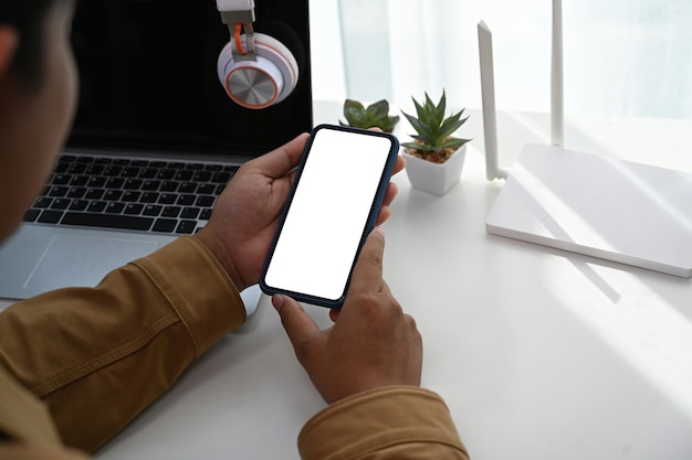 Vista de cerca de las manos del hombre usando un teléfono inteligente que conecta internet wifi en casa.