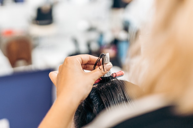 Vista de cerca de las manos de un peluquero con un rodillo para rizar el cabello de un cliente