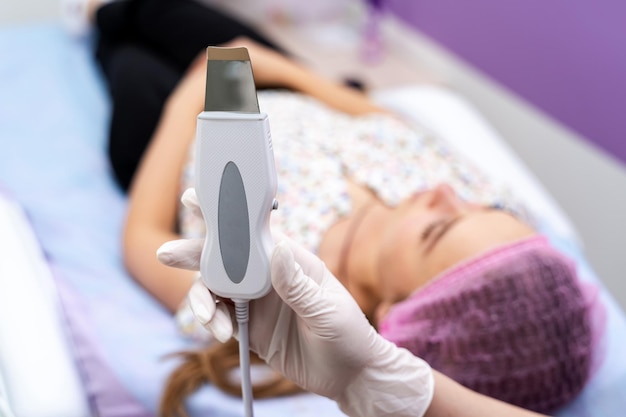 Foto vista de cerca de la máquina de ultrasonido cosmético. equipo de cosmetología en manos especializadas.