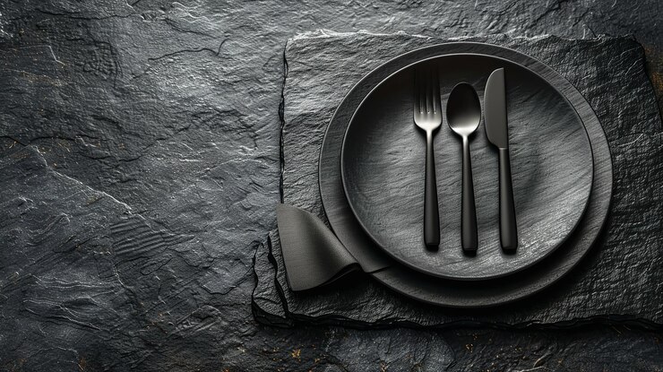 Una vista de cerca de una mesa con un cuchillo de tenedor de placa negra y una servilleta