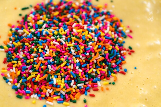 Foto vista de cerca mezclar ingredientes en un tazón de vidrio para hornear pastel funfettti bundt