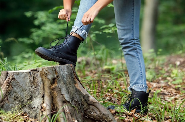 Vista de cerca de la mujer ata el cordón de su bota antes de caminar en un bosque