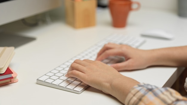 Vista de cerca de la mujer escribiendo en el teclado de la computadora en el cuadro blanco