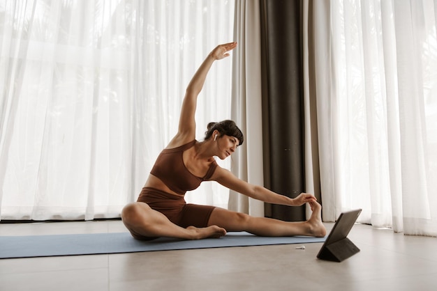 Vista de cerca de la mujer haciendo ejercicio de estiramiento en la computadora portátil