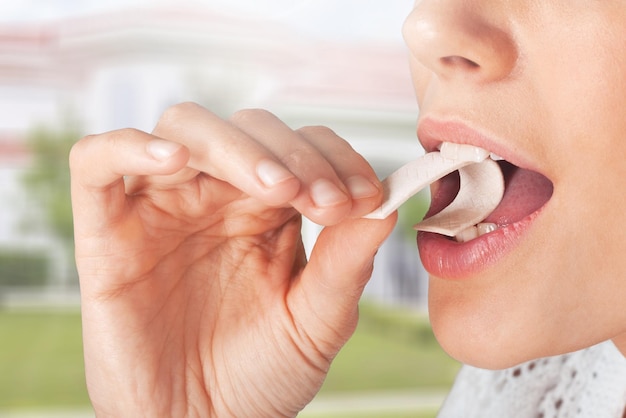 Foto vista de cerca de una mujer joven poniendo chicle en su boca