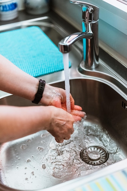 Vista de cerca de una mujer lavándose las manos con jabón y agua del grifo