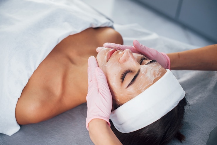 Foto vista de cerca de la mujer que está acostada en el salón de spa y tiene un procedimiento de limpieza facial con la máscara.