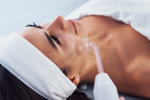 Vista de cerca de la mujer que está acostada en el salón de spa y tiene un procedimiento de limpieza facial.