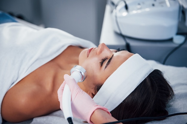 Vista de cerca de la mujer que está acostada en el salón de spa y tiene un procedimiento de limpieza facial.