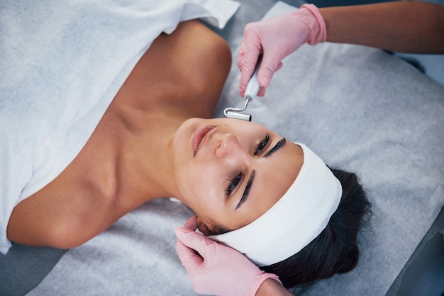 Vista de cerca de la mujer que está acostada en el salón de spa y tiene un procedimiento de limpieza facial.