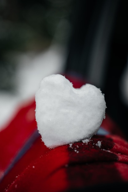 Vista de cerca de la nieve en forma de corazón en el concepto de día de San Valentín de bufanda de lana roja