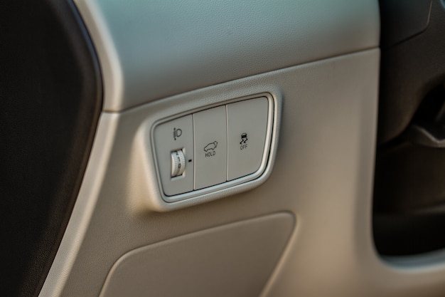 Vista de cerca del panel de control de los sistemas de seguridad electrónicos del coche moderno. Detalle interior del coche moderno. Botones de ajuste del corrector de faros.