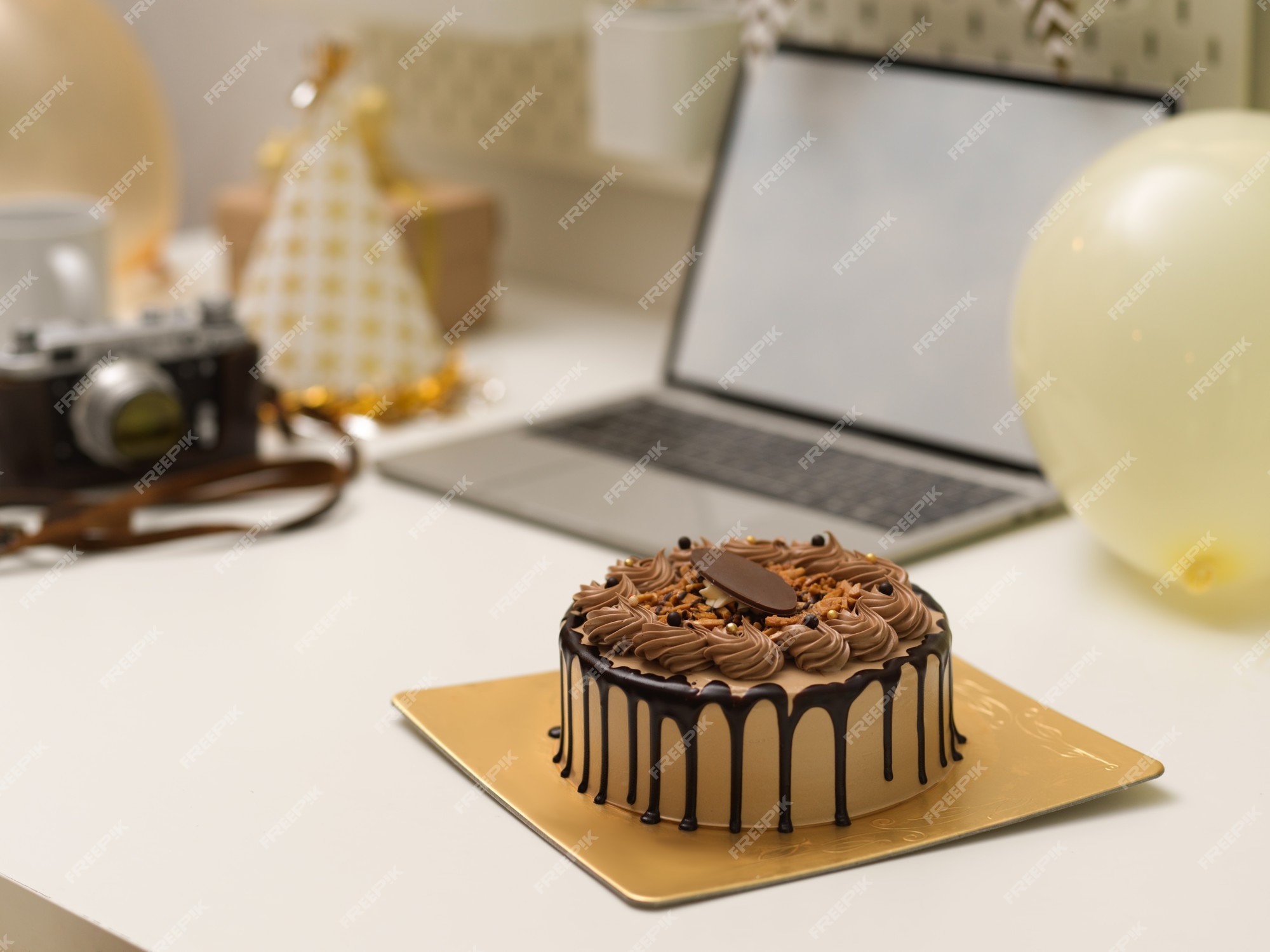 Vista de cerca del pastel de cumpleaños en la mesa con computadora  portátil, cámara y decoraciones, concepto de fiesta de cumpleaños en línea  | Foto Premium