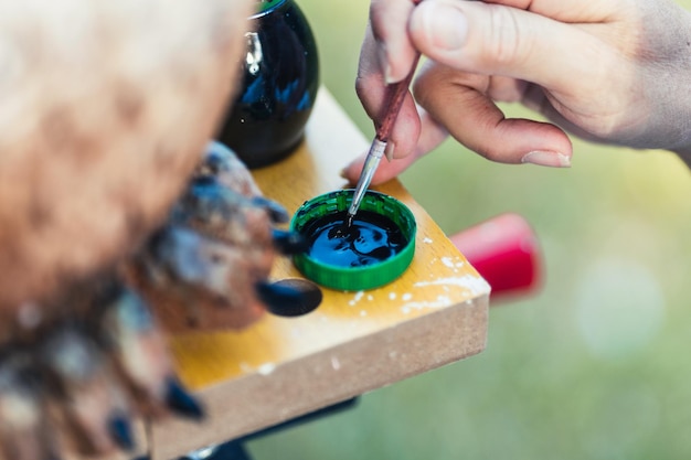 Vista de cerca de una persona mojando un pincel en pintura negra para pintar una figura hecha de poliestireno