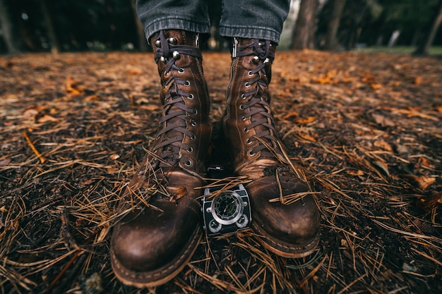 Vista de cerca en las piernas masculinas en botas de cuero vintage y relojes en otoño park