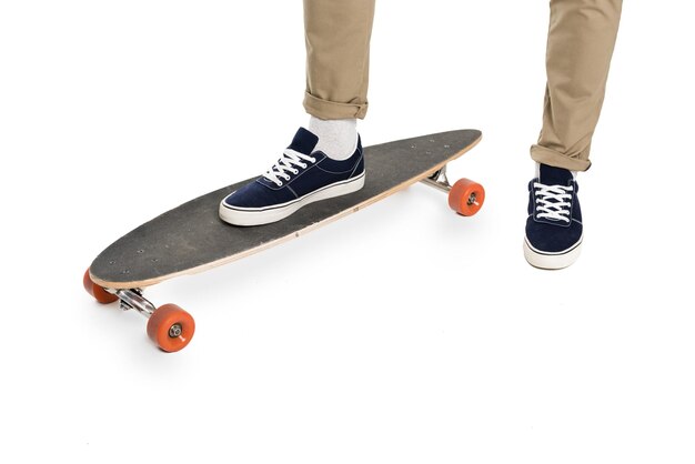 Foto vista de cerca de las piernas masculinas en calzado elegante y longboard aislado en blanco