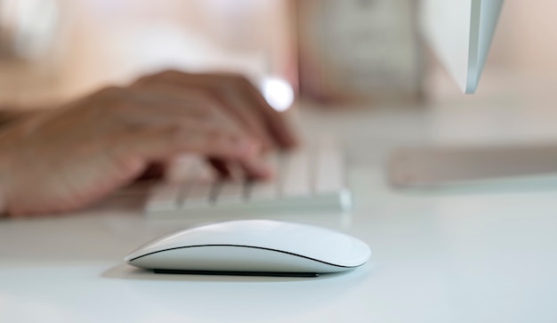 Vista de cerca del ratón blanco sobre la mesa blanca y escribiendo a mano sobre fondo de teclado