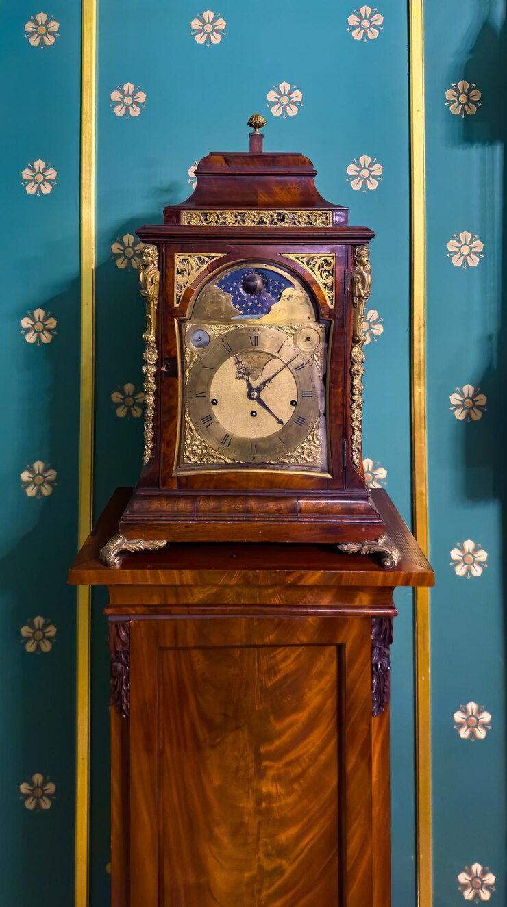 Una vista de cerca de un reloj de madera vintage con intrincados detalles de bronce colocados contra una rica pared de azul azul