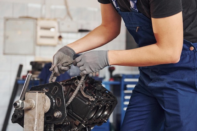 Vista de cerca del reparador profesional en el garaje que funciona con motor de automóvil roto