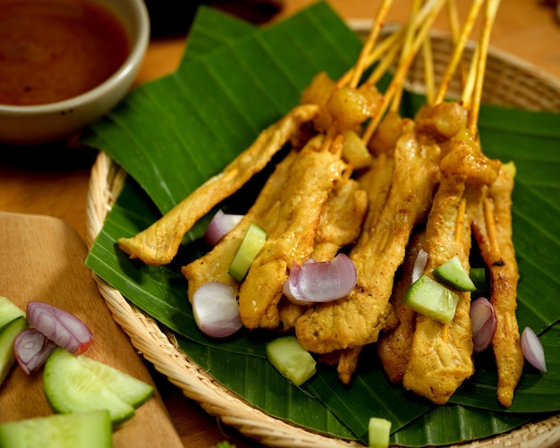 Vista de cerca de satay de cerdo a la parrilla (Moo Satay) con pepino y cebolla