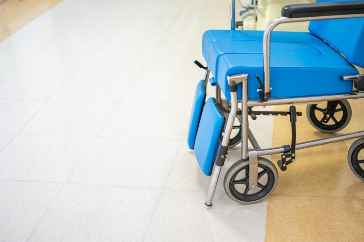 Vista de cerca de la silla de ruedas acolchada azul especializada con el pasillo del hospital en segundo plano