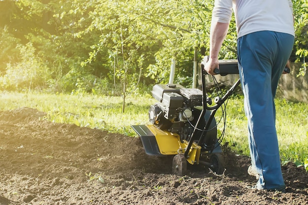 Una vista de cerca sobre el motor cultivador durante el proceso de arado de la temporada de primavera concepto de obras de jardinería