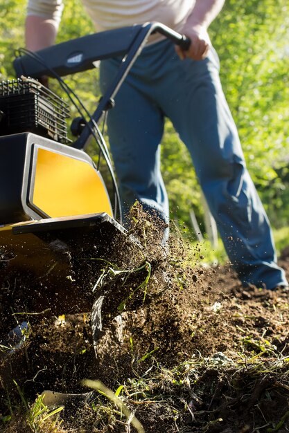 Una vista de cerca sobre el motor cultivador durante el proceso de arado de la temporada de primavera concepto de obras de jardinería