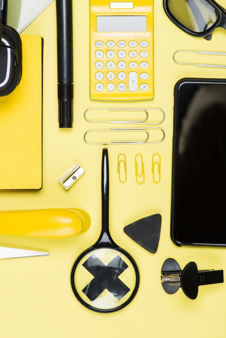 Foto vista de cerca del teléfono inteligente calculadora y útiles escolares en amarillo