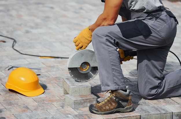 Vista de cerca Trabajador masculino en uniforme de color amarillo tiene trabajo con pavimento