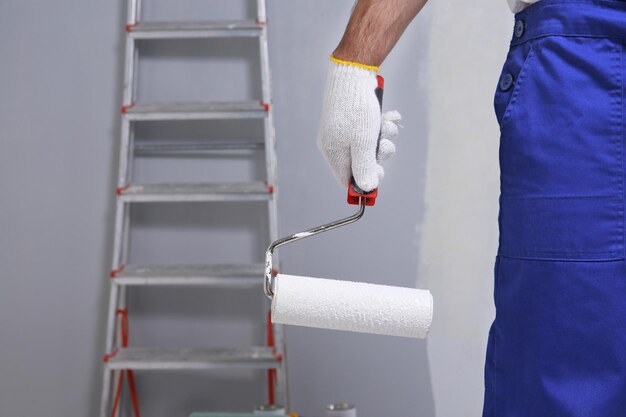 Vista de cerca del trabajador con rodillo de pintura en la habitación