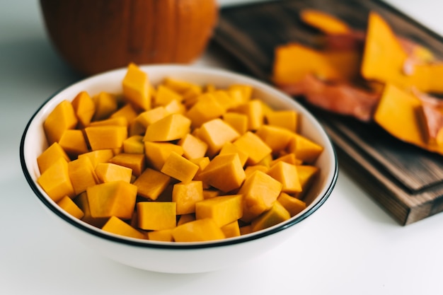 Vista de cerca de trozos de calabaza naranja viva y fresca en un plato blanco.