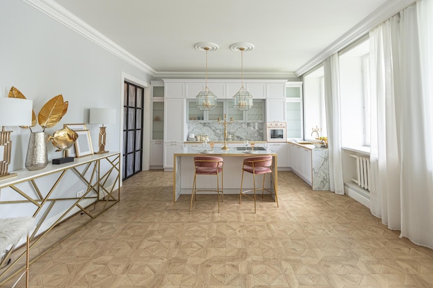 Una vista cercana de la elegante cocina blanca con una isla de cocina en el lujoso interior de un apartamento moderno en colores claros con muebles elegantes