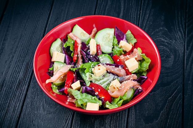 Vista cercana de ensalada casera fresca con salmón, tomate, pepino, lechuga y queso