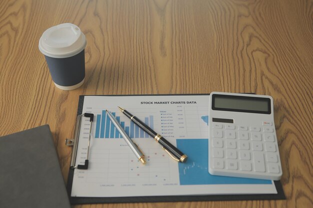 Foto vista cercana de un espacio de trabajo simple con portátiles, cuadernos, taza de café y olla de árbol en una mesa blanca con fondo borroso de la habitación de la oficina