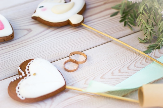 Foto vista cercana de galletas en forma de corazón bisquits en bastón y anillos de boda.