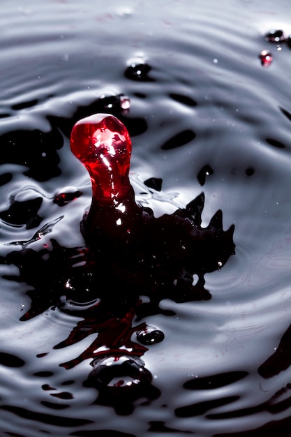 Foto vista cercana de una gotita de vino golpeando una superficie de vino.