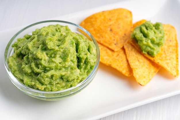 Vista cercana de guacamole salsa mexicana vegetariana de aguacate servida con nachos como refrigerio saludable