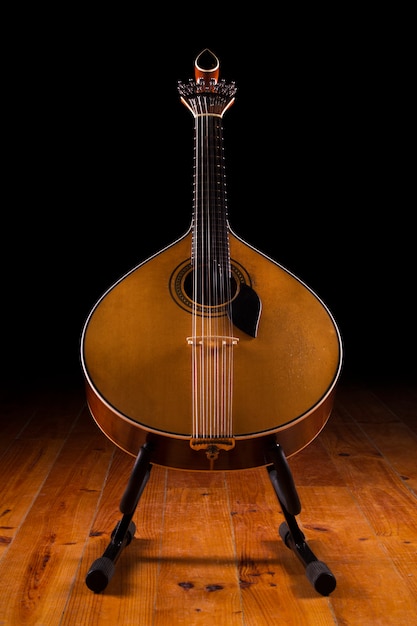 Vista cercana de una guitarra portuguesa tradicional en un fondo oscuro.