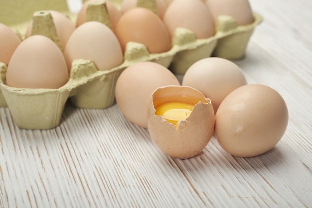 Vista cercana de huevos de gallina crudos en caja de huevos sobre fondo de madera. Huevos de gallina crudos en caja de huevos alimentos orgánicos para una buena salud con alto contenido de proteínas.