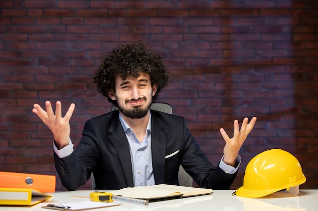 Vista cercana ingeniero masculino sentado detrás del lugar de trabajo en traje contratista constructores de negocios trabajo agenda de trabajo